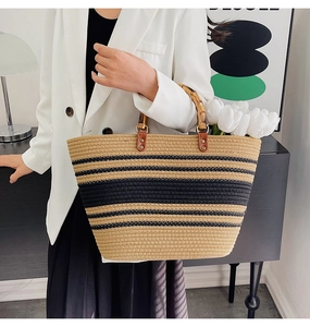 Detail shot of a woven tote bag with bamboo handles and striped pattern on a model