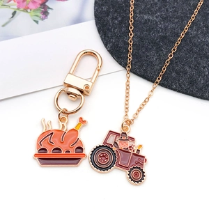 Detail of enamel roasted turkey keychain and gold tractor pendant necklace accessory set