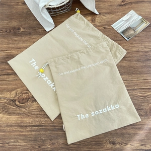 Travel drawstring storage bags in beige fabric set on a rustic wood floor for travel