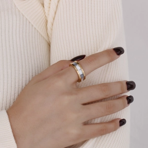 Detailed close-up of a gold-plated stainless steel ring with white shell inlay on finger
