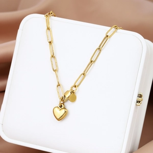 Macro shot of gold paperclip chain bracelet with a 3D heart pendant on a silk background