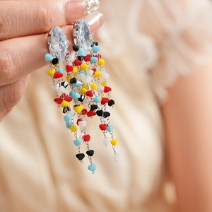 Macro view of colorful beaded tassel earrings with crystal studs and metal chains