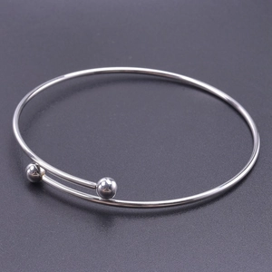 Close-up of polished silver stainless steel cuff with adjustable bypass design and twin beads