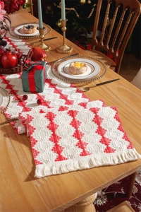 Detailed close-up of red and white cotton table runner with tassels on a wooden table