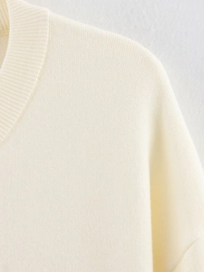 Primer plano detallado de la textura de punto crema y costuras del escote del cárdigan