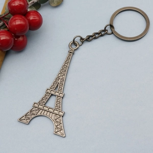Vintage bronze Eiffel Tower metal keychain with ring and chain on light blue background