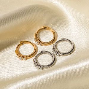 Orecchini a cerchio in oro e argento con tre piccole perle su sfondo di seta