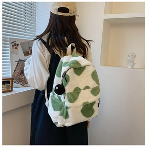 Detail of plush backpack with green polka dots, furry texture and cute coal sprite charm