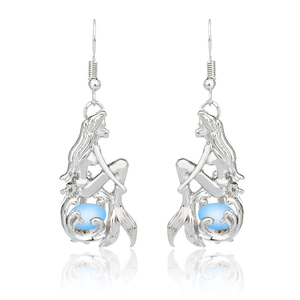 Detail of silver mermaid hook earrings featuring a luminous light blue bead on white background
