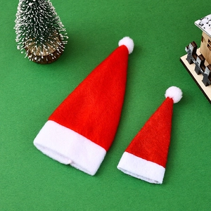 Pair of mini red and white felt Christmas hats on a festive holiday green background