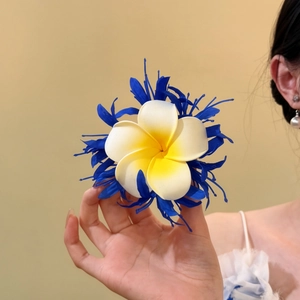 Detailansicht einer stilvollen blau-weißen Plumeria-Haarklammer aus Stoff in der Hand
