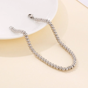 Minimalist stainless steel 4mm bead bracelet with lobster clasp on a white plate