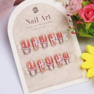 Detail of pink gradient press-on nails with white flower patterns and pearl accents