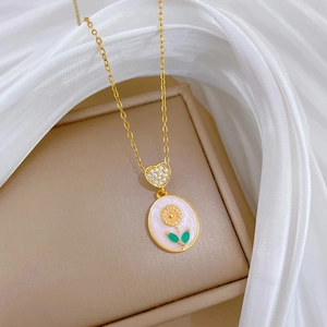 Detail of gold heart necklace with pink floral enamel pendant on white silk fabric
