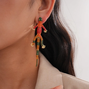 Detailed close-up of a long gold lizard earring with colorful rhinestones on a model