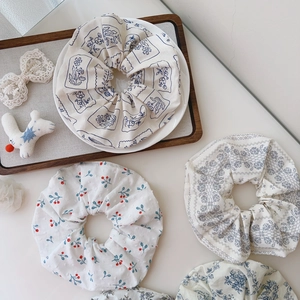 Flat lay of cotton floral scrunchies with various patterns on a wooden tray