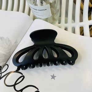 Detail of large matte black petal hair claw clip on magazine for elegant hairstyling