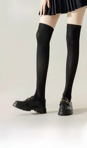 Detalle de medias negras por encima de la rodilla con lazo en las piernas de la modelo