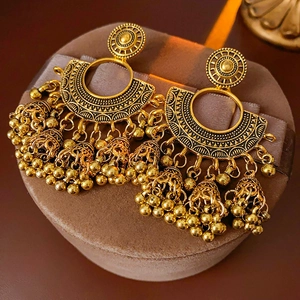 Macro shot of vintage gold tassel earrings with ethnic lantern bells on brown velvet