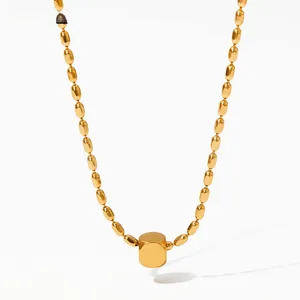 Detail view of a gold oval bead chain necklace with a minimalist cylindrical pendant
