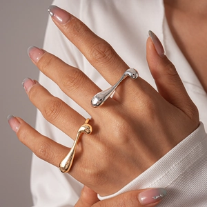 Detailed view of liquid metal gold and silver irregular geometric rings on model hand