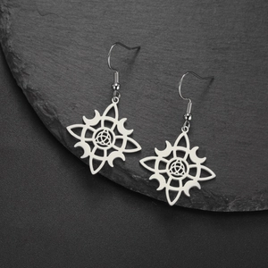 Detailed view of stainless steel moon witch knot earrings on a grey slate stone background