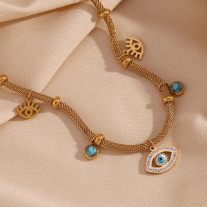 Detail of gold evil eye necklace with blue turquoise beads and white zircon on silk