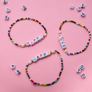 Close-up of colorful beaded bracelets set featuring Happy and Love letter acrylic beads