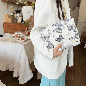 Detail of white lace butterfly cosmetic bag featuring frayed edges and fabric brand label