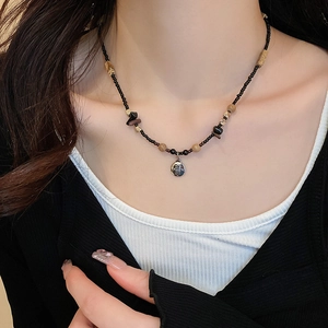 Close-up of black and earth-toned beaded necklace with a round silver butterfly pendant