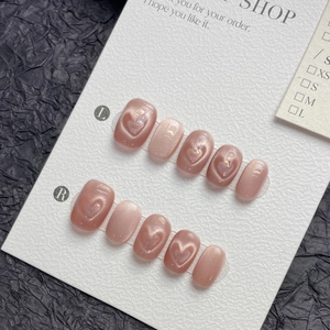 Pink cat eye press-on nails with 3D crystal hearts on a textured white card