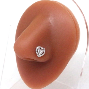 Macro shot of silver heart-shaped nose stud with sparkling white zircons on a model