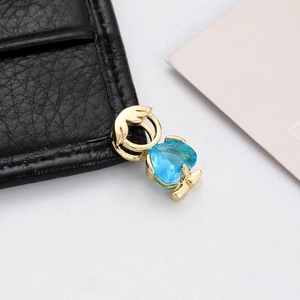 Close-up of golden boy charm with blue heart zircon pendant for DIY jewelry
