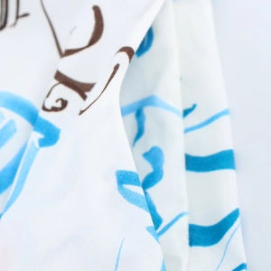 Macro detail of the white fabric with blue and brown abstract art patterns and soft texture