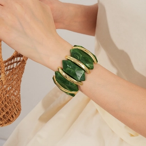 Gros plan sur un bracelet en acrylique marbre vert avec détails dorés au poignet