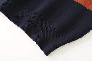 Detailed macro view of the navy blue and orange striped ribbed knit sweater hemline