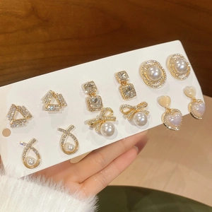 Close-up of gold earring set with pearls and rhinestones on a display card