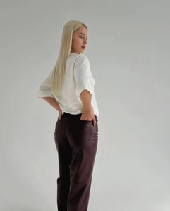 Vue détaillée du dos d'un t-shirt blanc associé à un pantalon en simili cuir foncé