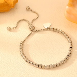 Silver stainless steel heart charm bracelet with adjustable beads on white background