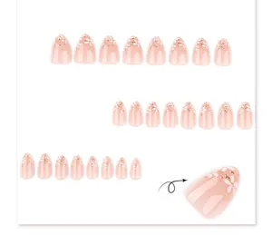 Détail de faux ongles en amande avec fleurs 3D blanches et touches de paillettes dorées