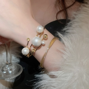 Detail of layered gold bangles with pearls and small diamonds on a model's wrist