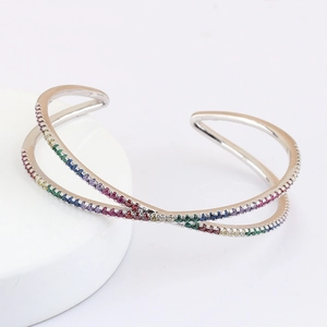 Macro detail of silver crossover open bangle with rainbow pavé cubic zirconia stones