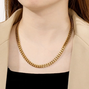 Collana a catena cubana in acciaio al titanio dorato indossata da un modello in blazer beige