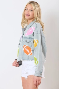 Detail of light blue denim jacket with colorful sequined football patches and metal buttons