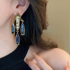 Close-up of vintage baroque gold earrings with deep blue and clear teardrop crystals