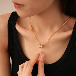 Primo piano della collana con ciondolo a cilindro dorato e zirconi sulla clavicola