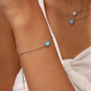 Close-up detail of the stainless steel bracelet featuring a pear-shaped opal pendant and chain.