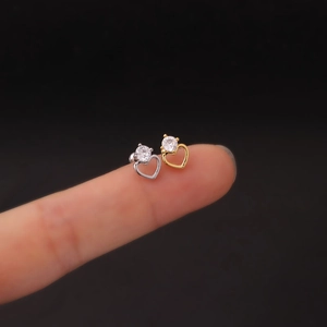 Macro shot of small heart earrings in gold and silver finish on fingertip detail