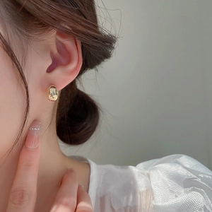 Elegant gold bean stud earrings for women with a smooth metallic finish on the earlobe