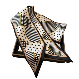 Polka dot and geometric striped long silk scarf displayed on a grey gift box